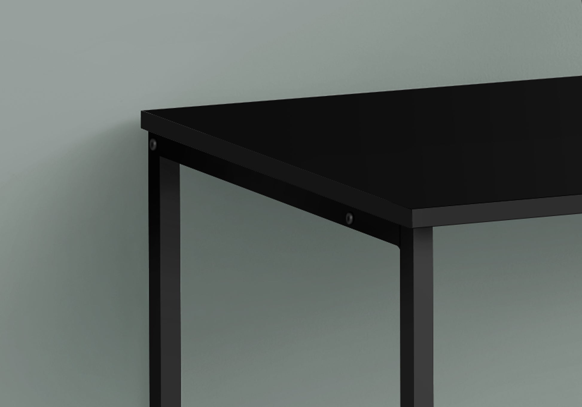Closeup of a sleek black metal desk frame with a matching matte black tabletop