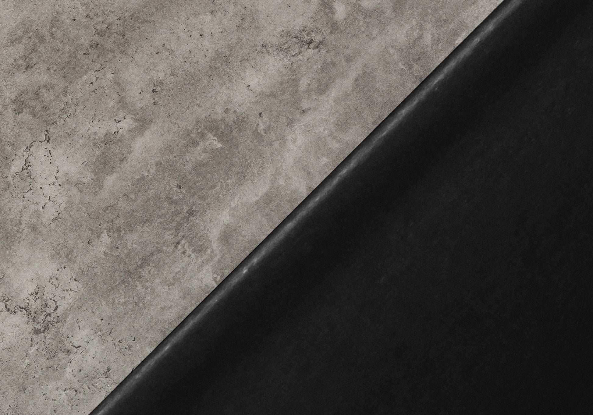 Textured grey concrete slab with a smooth black surface diagonally split