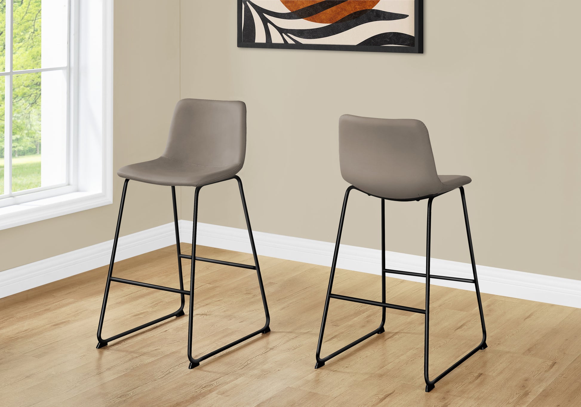 Two taupe leatherette bar stools with black metal legs and a modern design