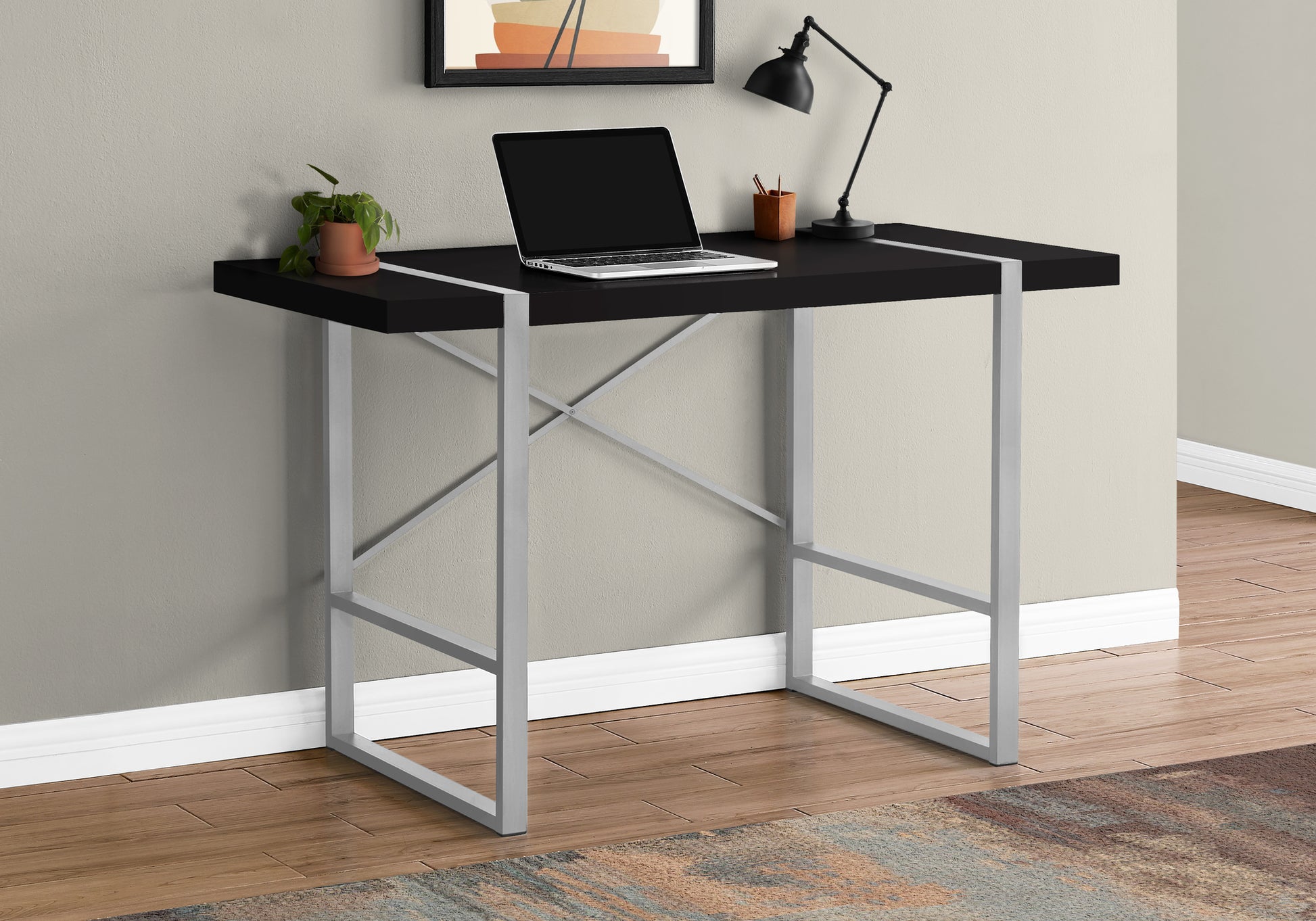 Sleek black modern desk with silver metal Xframe legs and a laptop