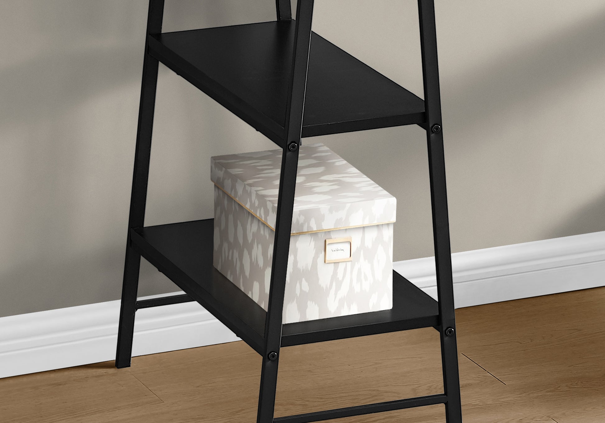 Black metal ladder shelf with decorative storage box holding books