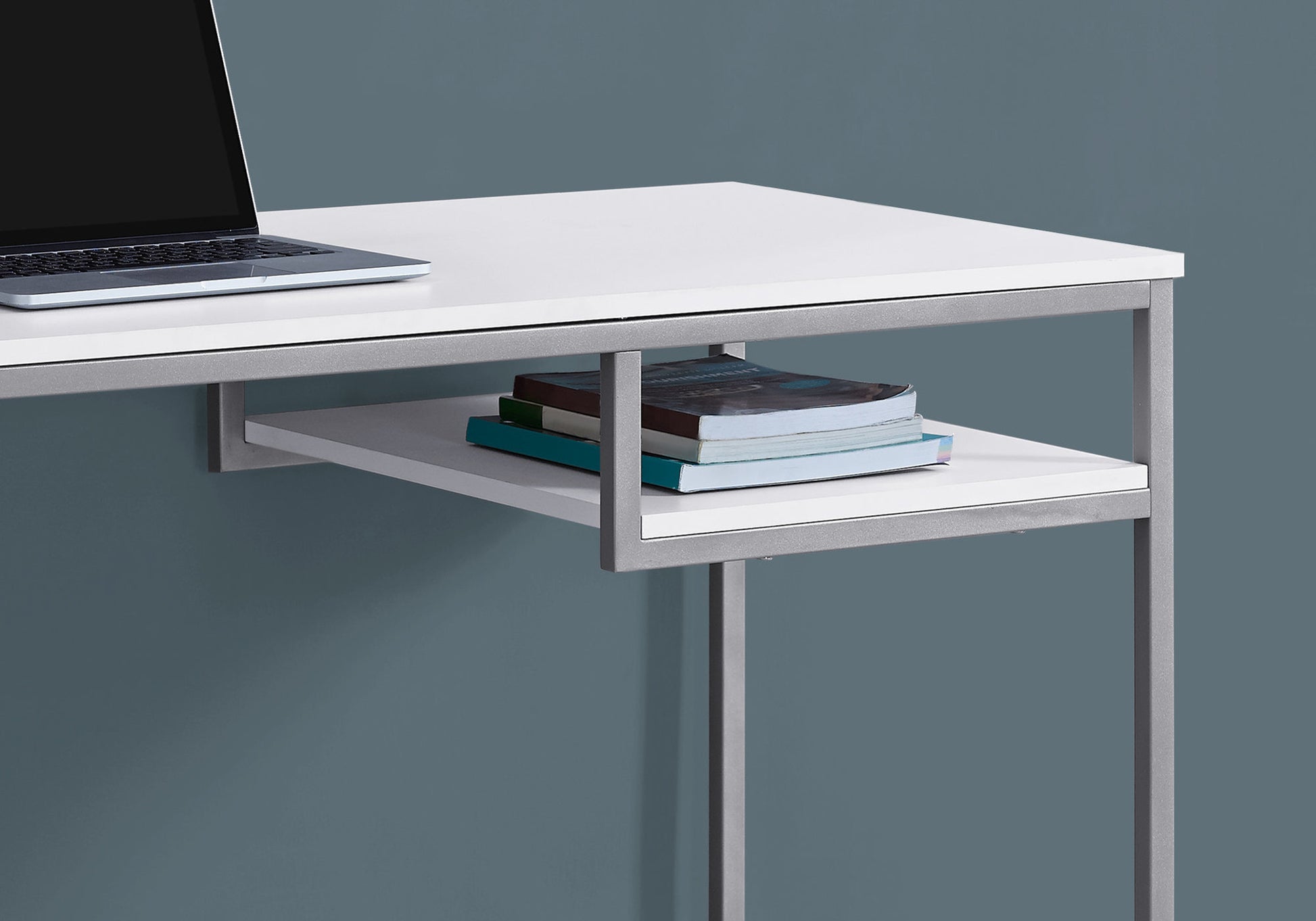 White minimalist desk with sleek silver frame and stacked books