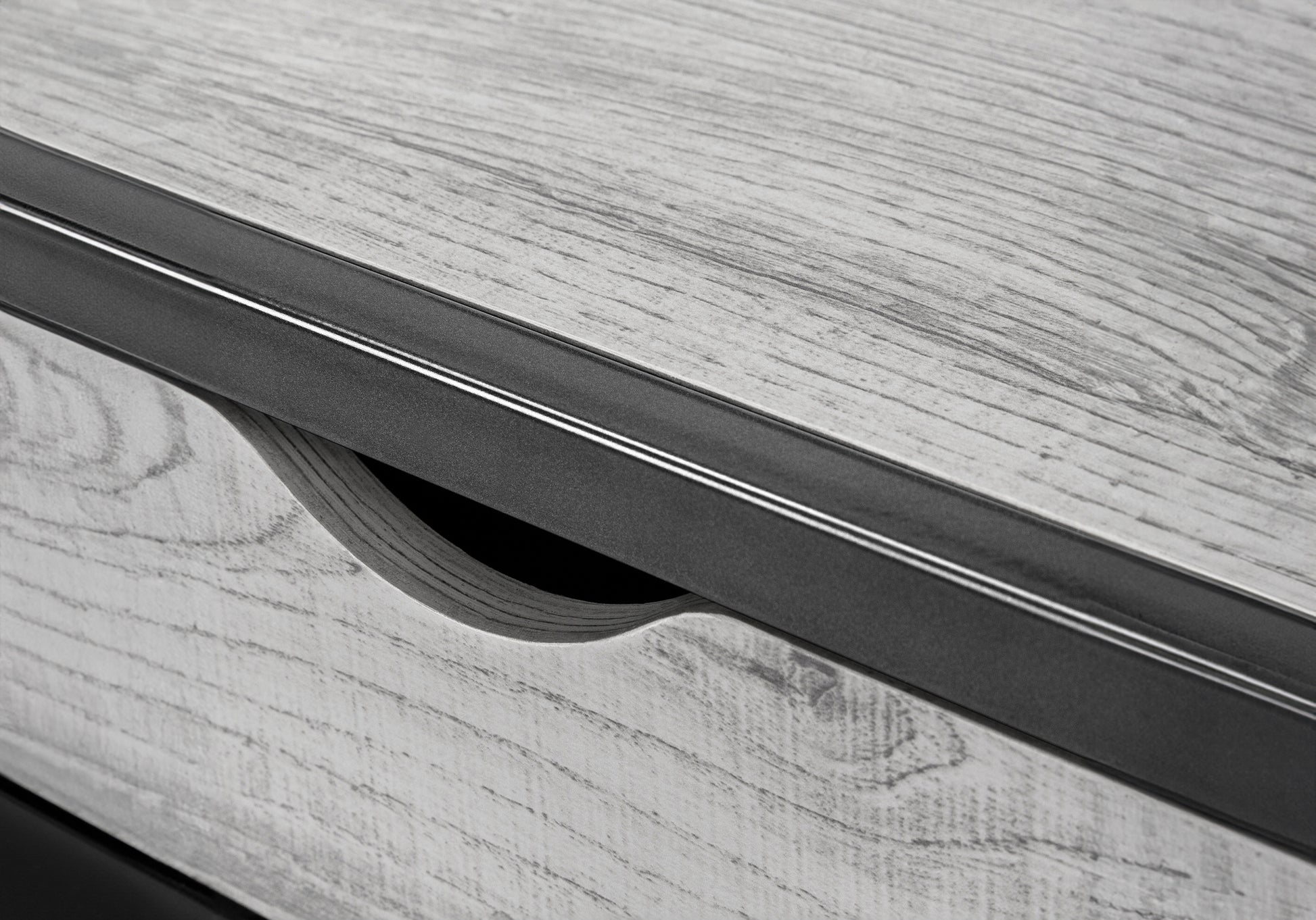 Close up of grey wood grain texture with a modern black metal drawer pull