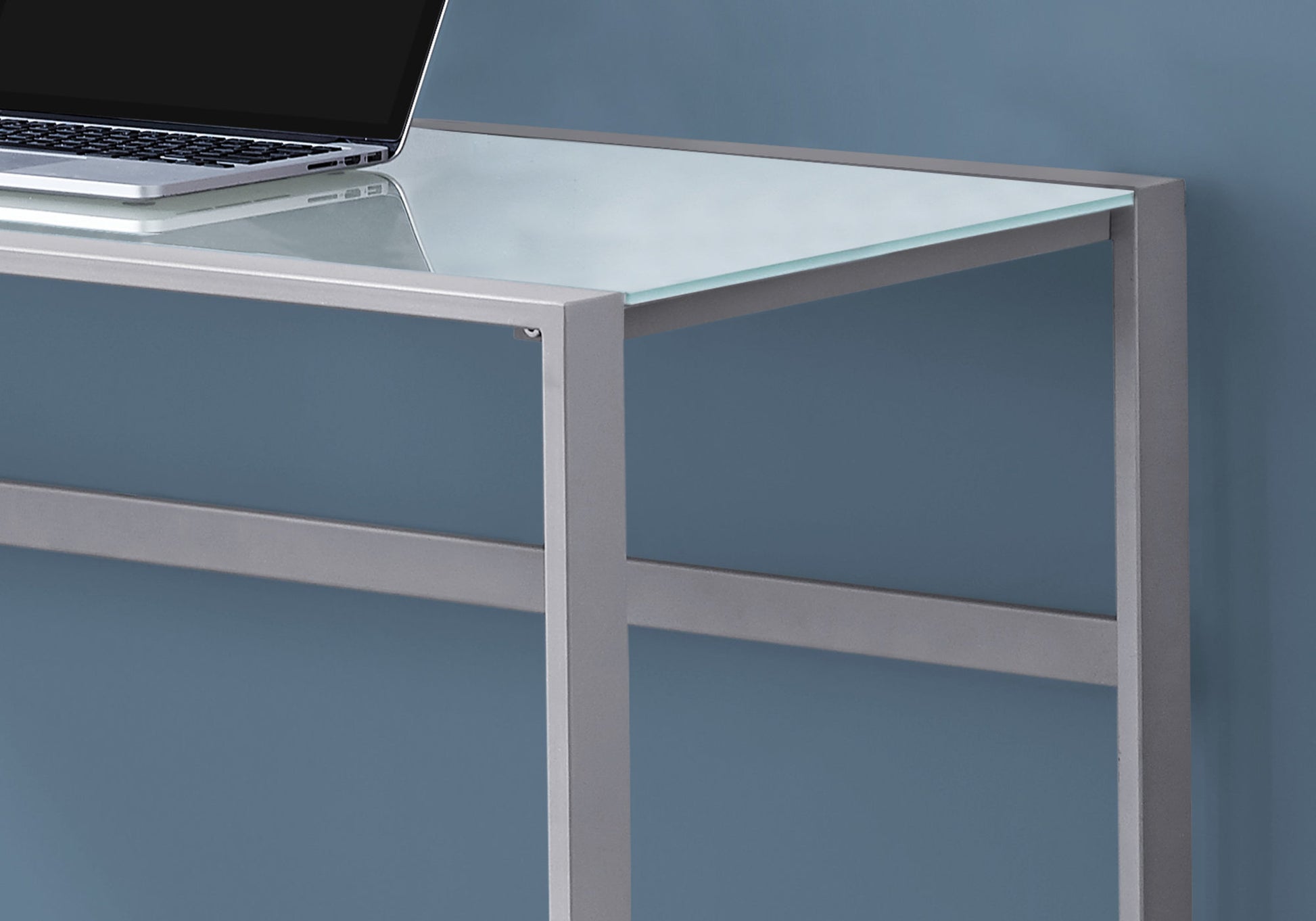 Modern glass desk with silver metal frame and a laptop