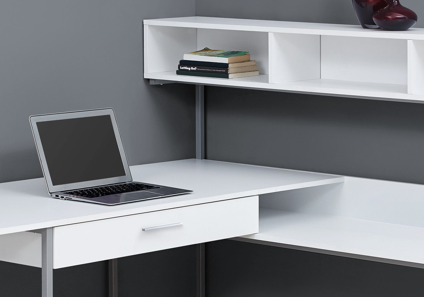 Modern white desk with open shelving and a laptop