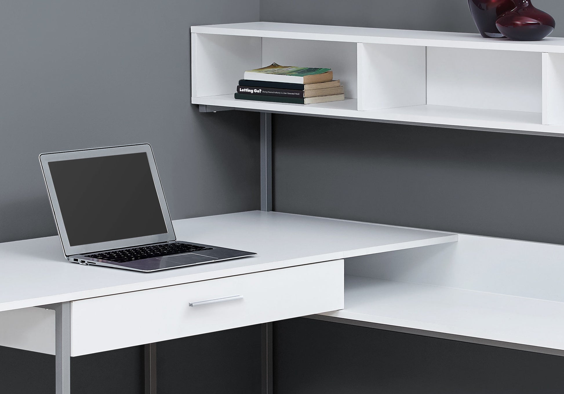 Modern white desk with open shelving and a laptop
