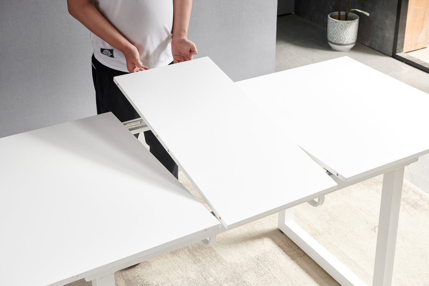 White extendable dining table being assembled by a person