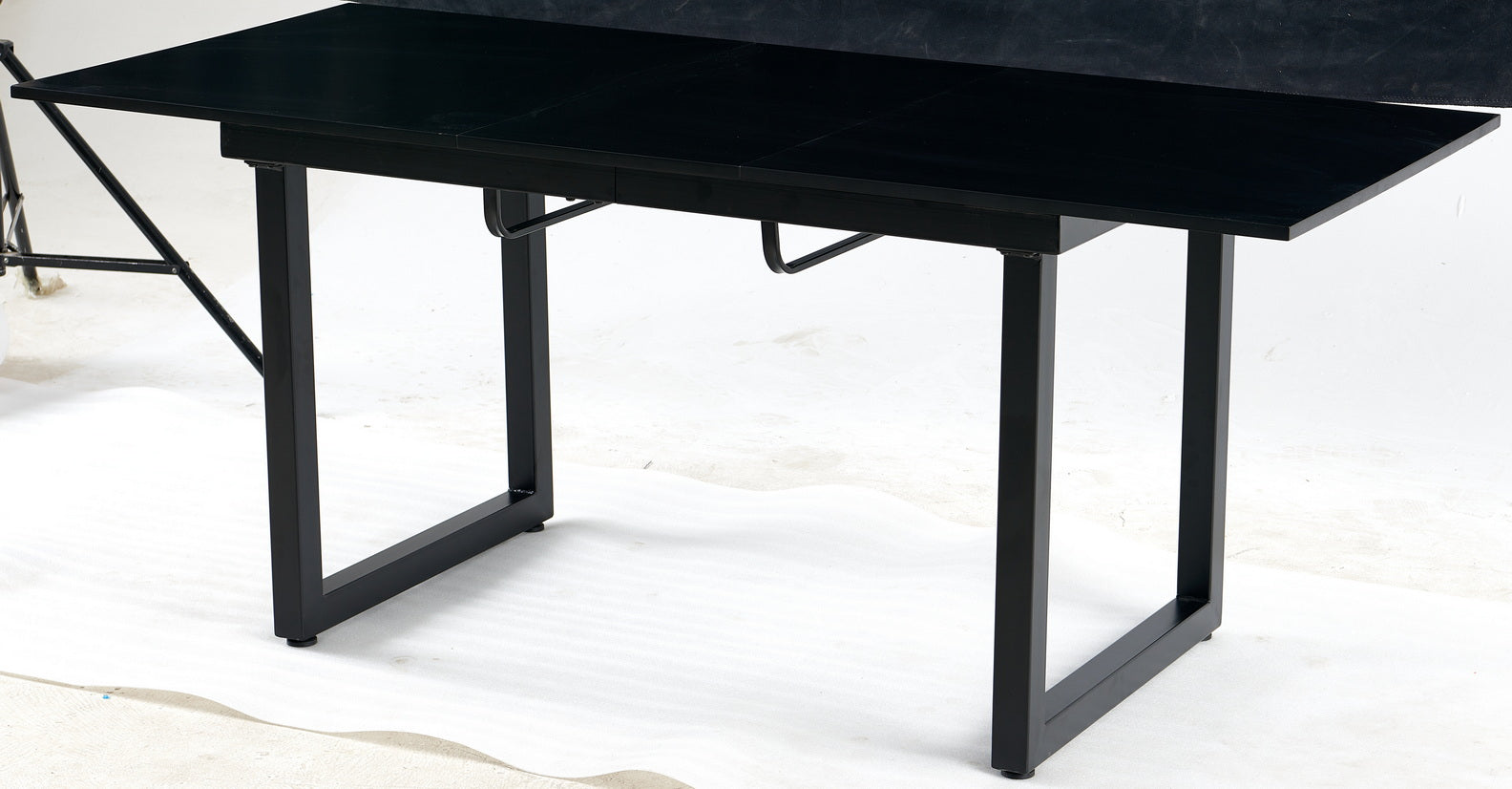Black extendable dining table with metal legs and a matte finish