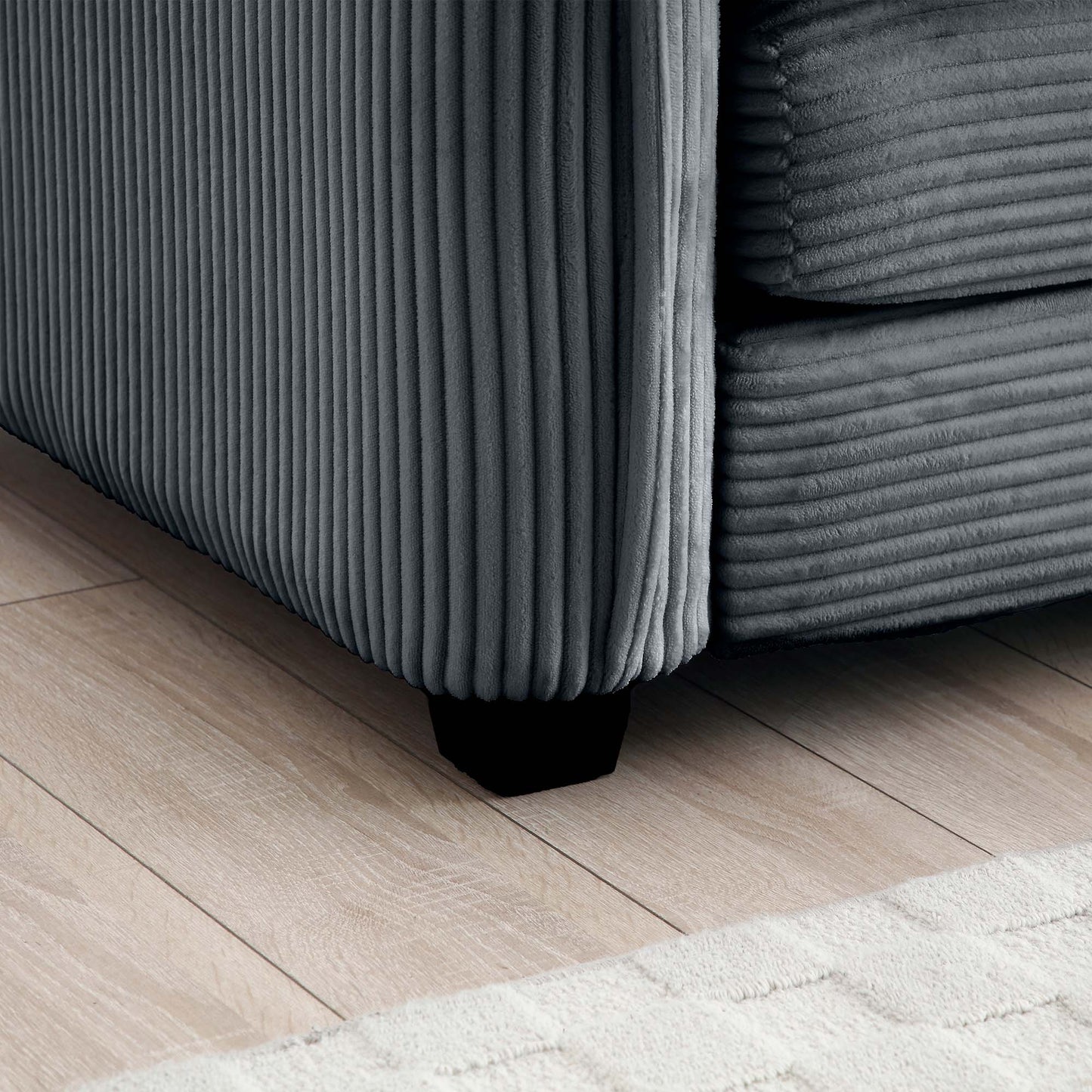 Dark grey corduroy sofa section with thick vertical ribs and a black leg