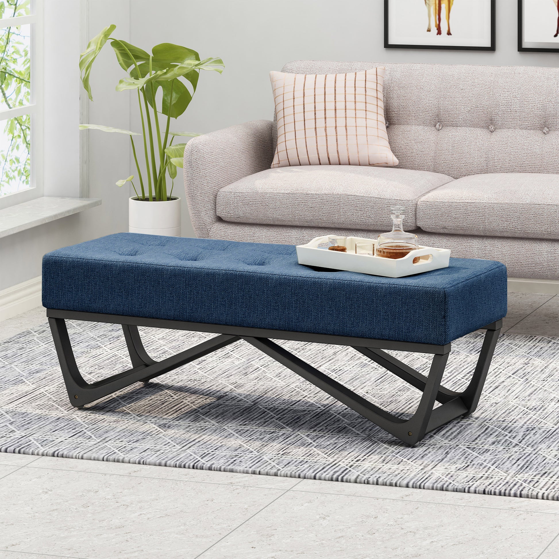 Blue tufted ottoman bench with black metal legs on a patterned rug