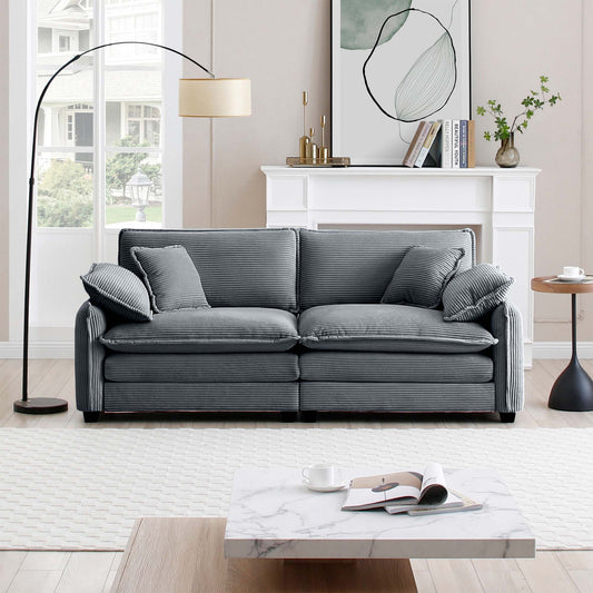 Plush grey corduroy sofa with tufted seat cushions and decorative throw pillows