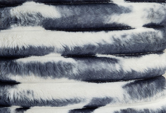 Plush faux fur throw with a cow print design in black and white perfect for cozy decor