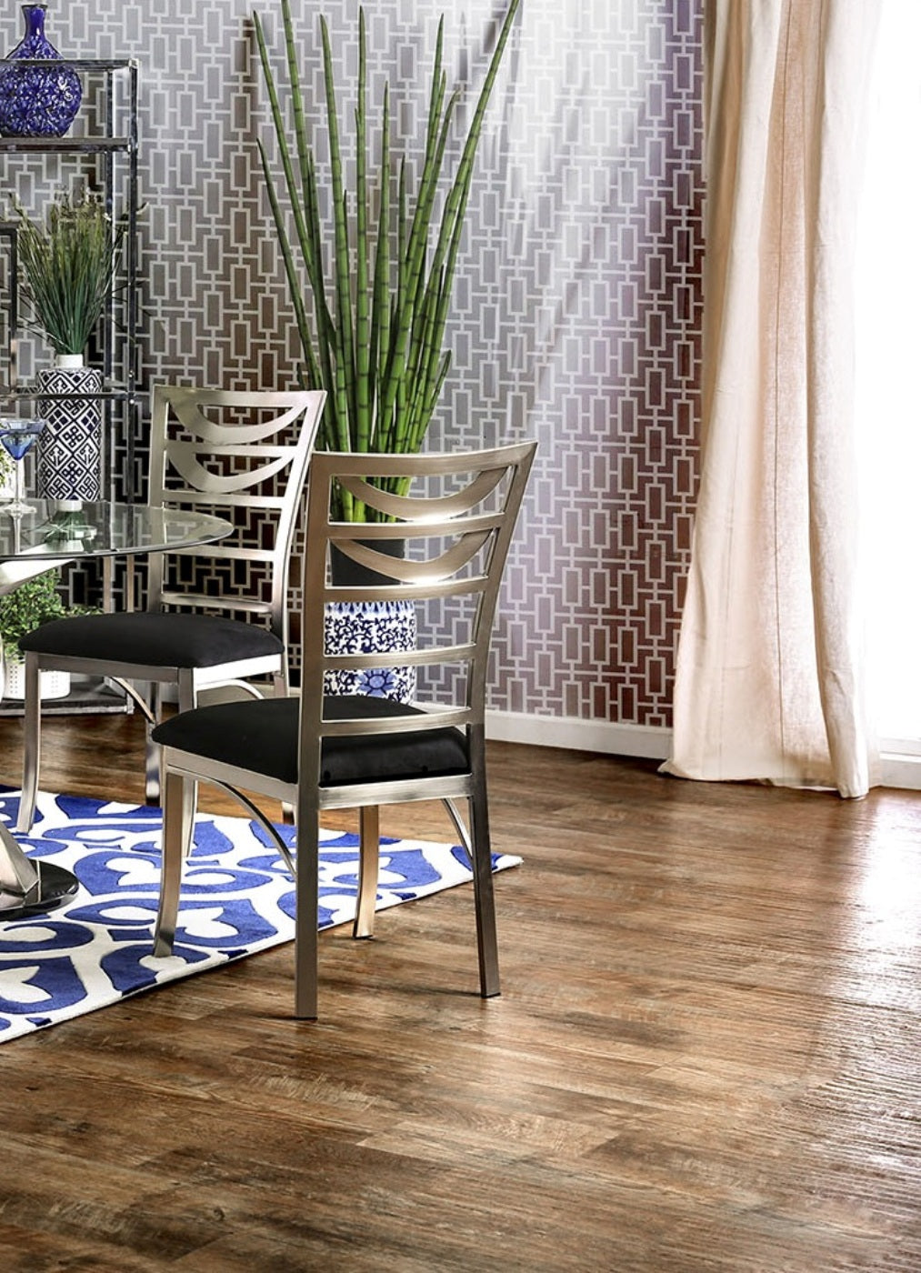 Modern silver dining chair with black upholstered seat on a blue and white rug