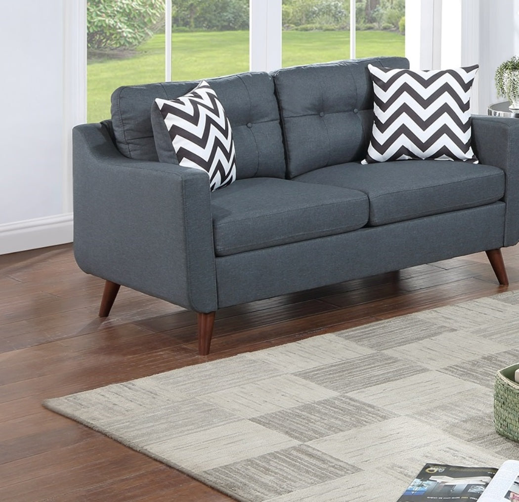 Dark gray upholstered sofa with tufted back and chevron pillows on wooden legs