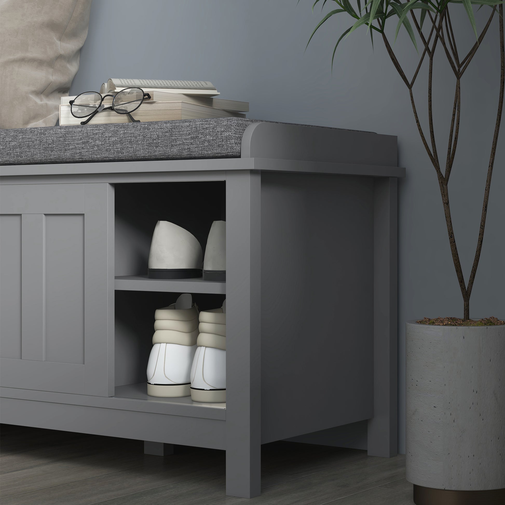 Gray entryway bench with cushioned seat and two shelves storing shoes