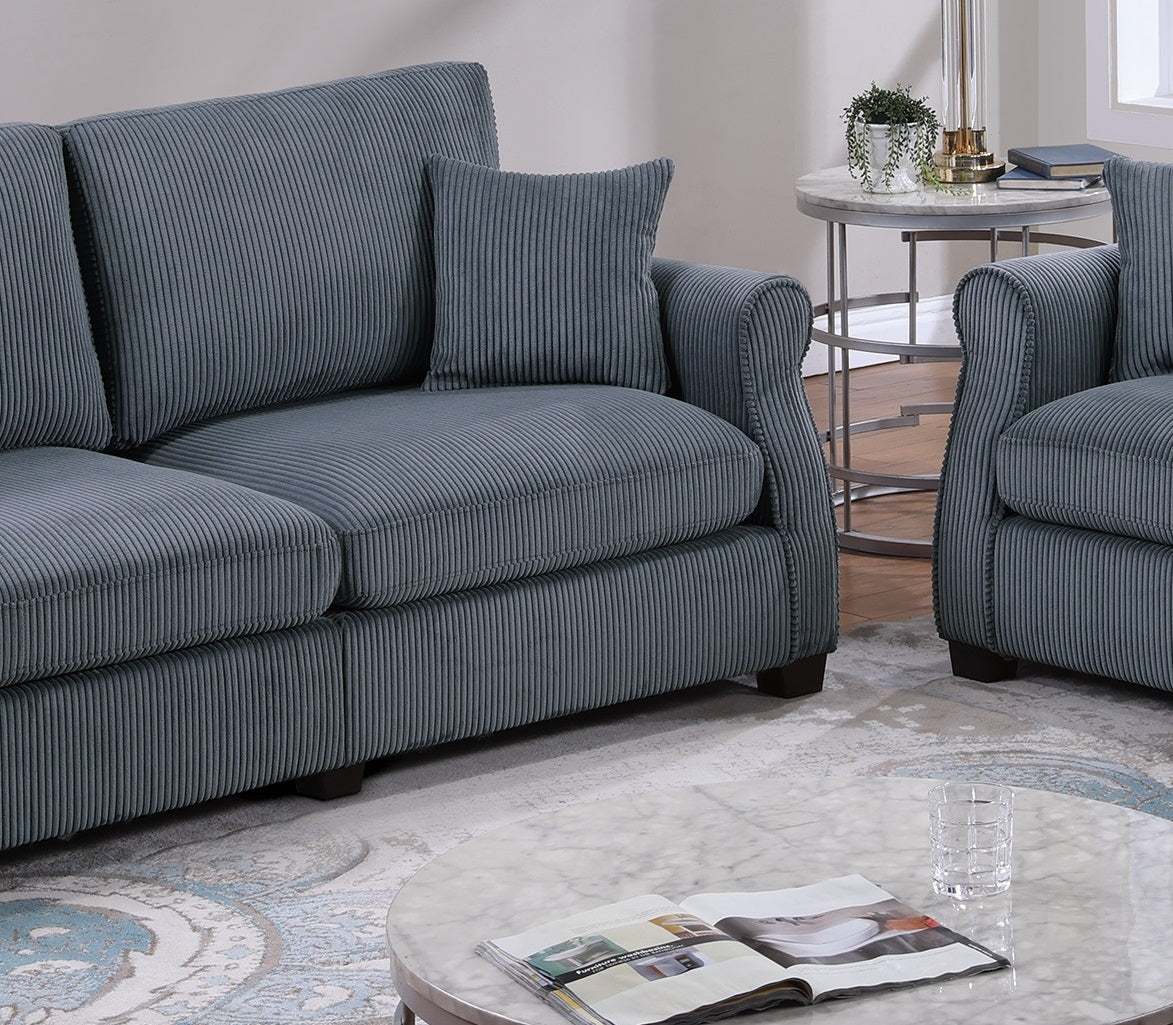 Closeup of a plush blue corduroy sofa with detailed stitching and a matching throw pillow
