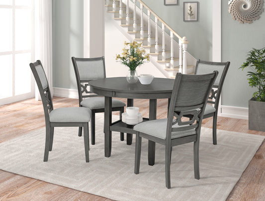 Gray round dining table with four upholstered chairs and a stacked plate set