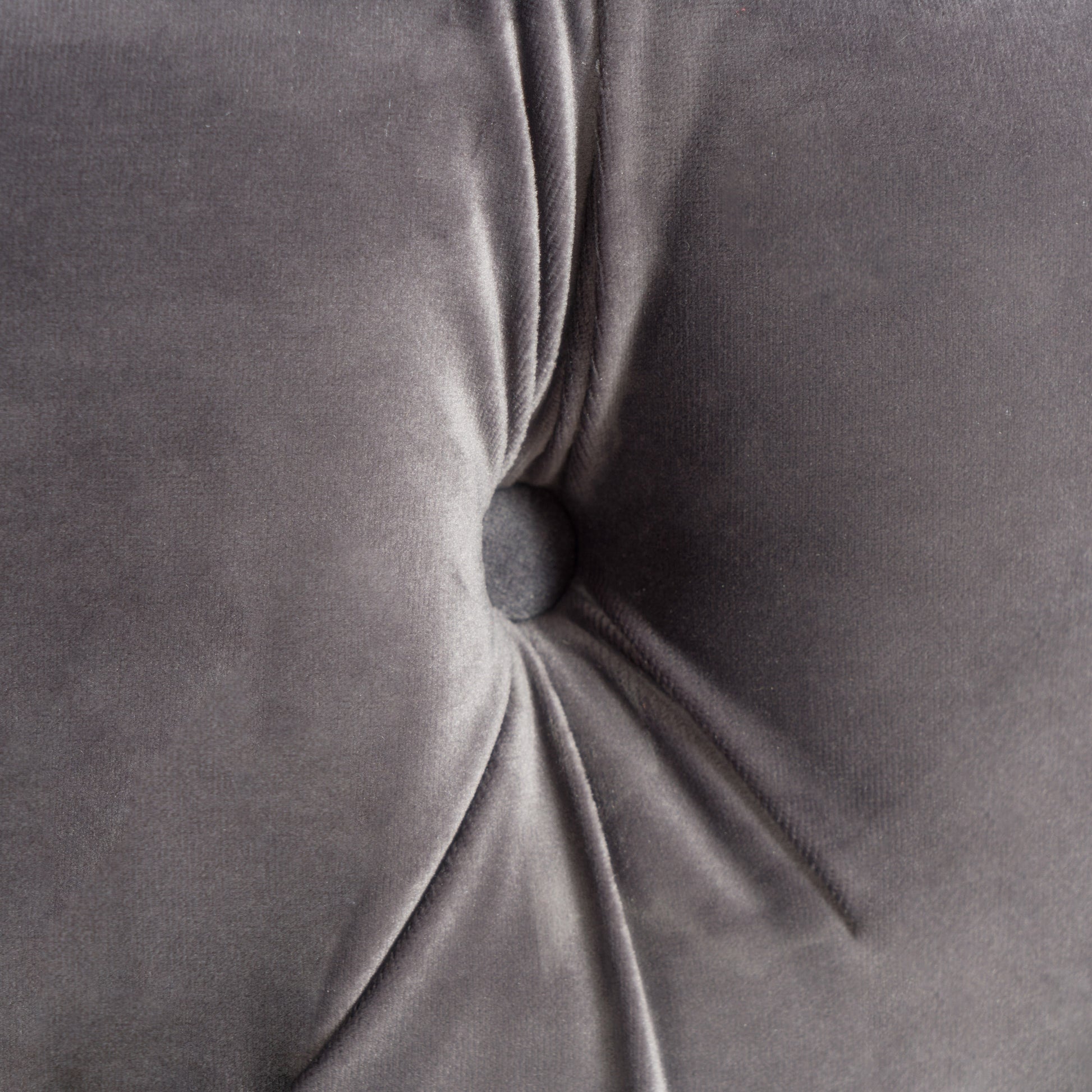 Closeup of tufted grey velvet fabric with a button accent
