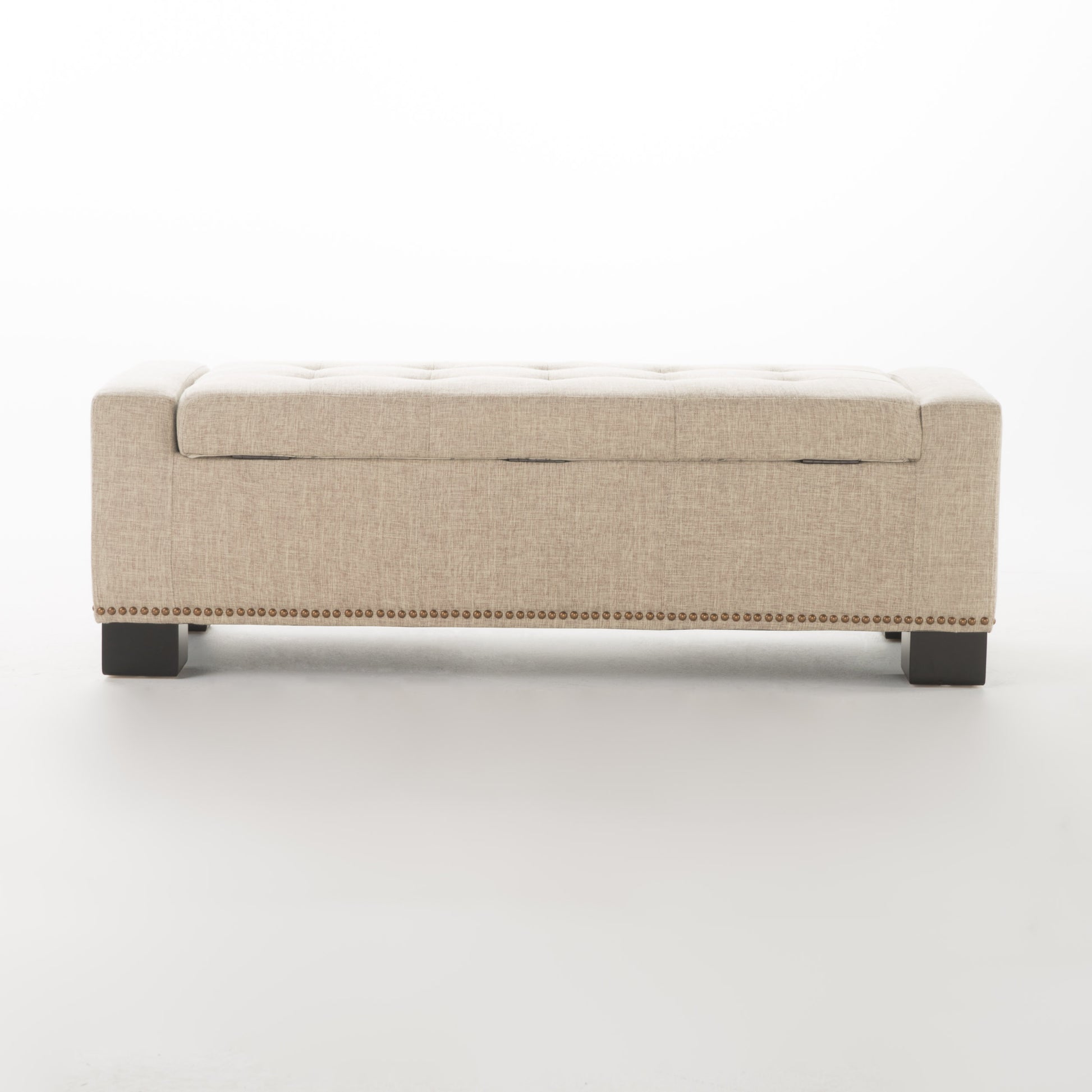 Beige tufted storage ottoman with brass nailhead trim