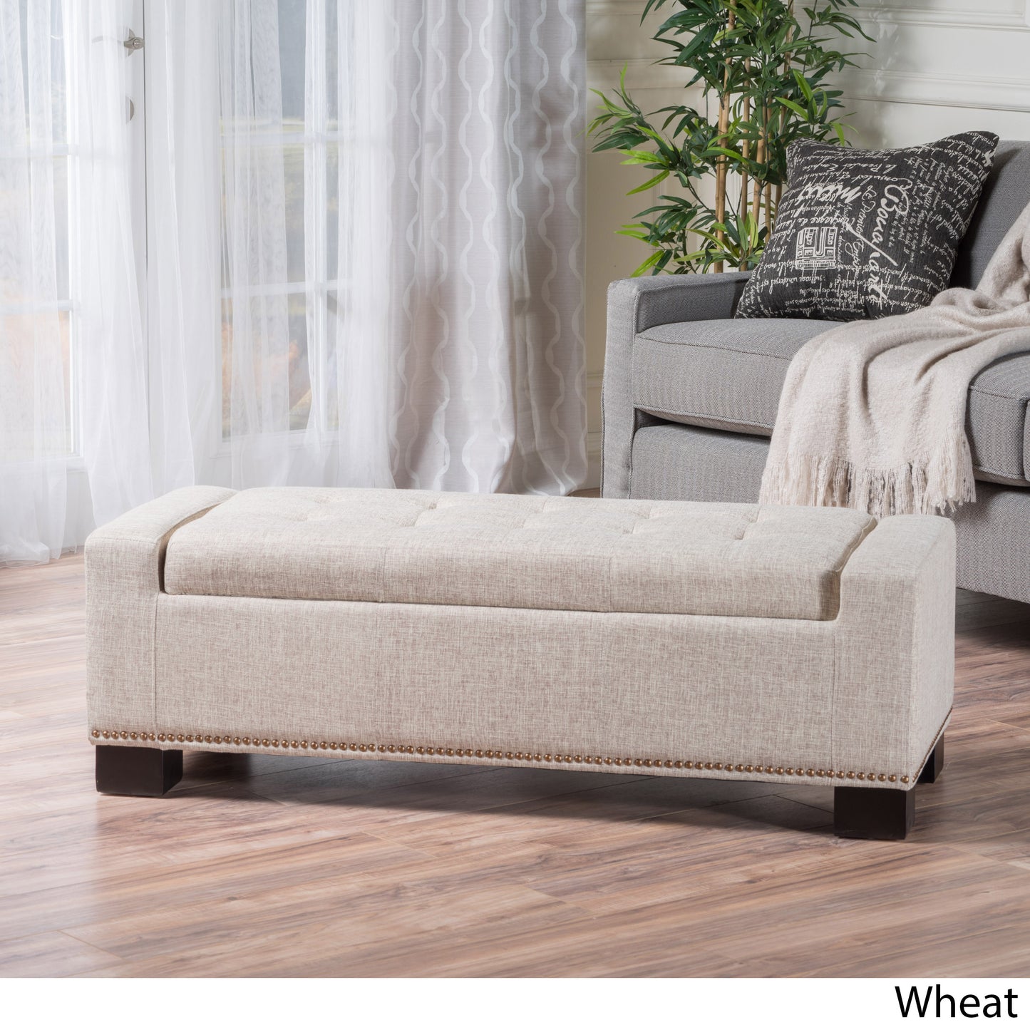 Tufted wheat linen storage ottoman with decorative nailhead trim and dark wood legs