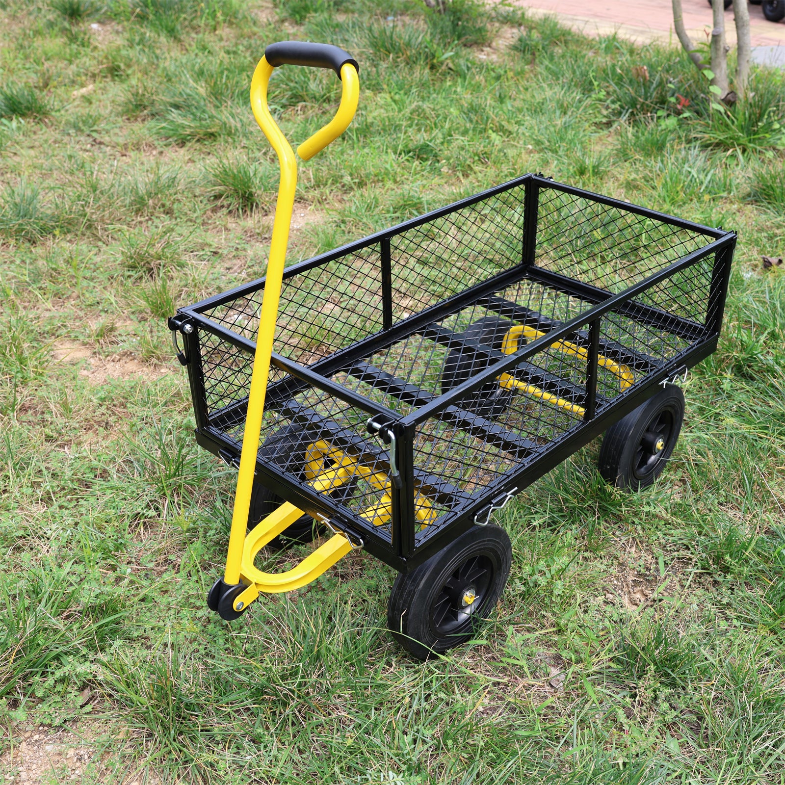 Black metal garden cart with yellow handle and frame on grass