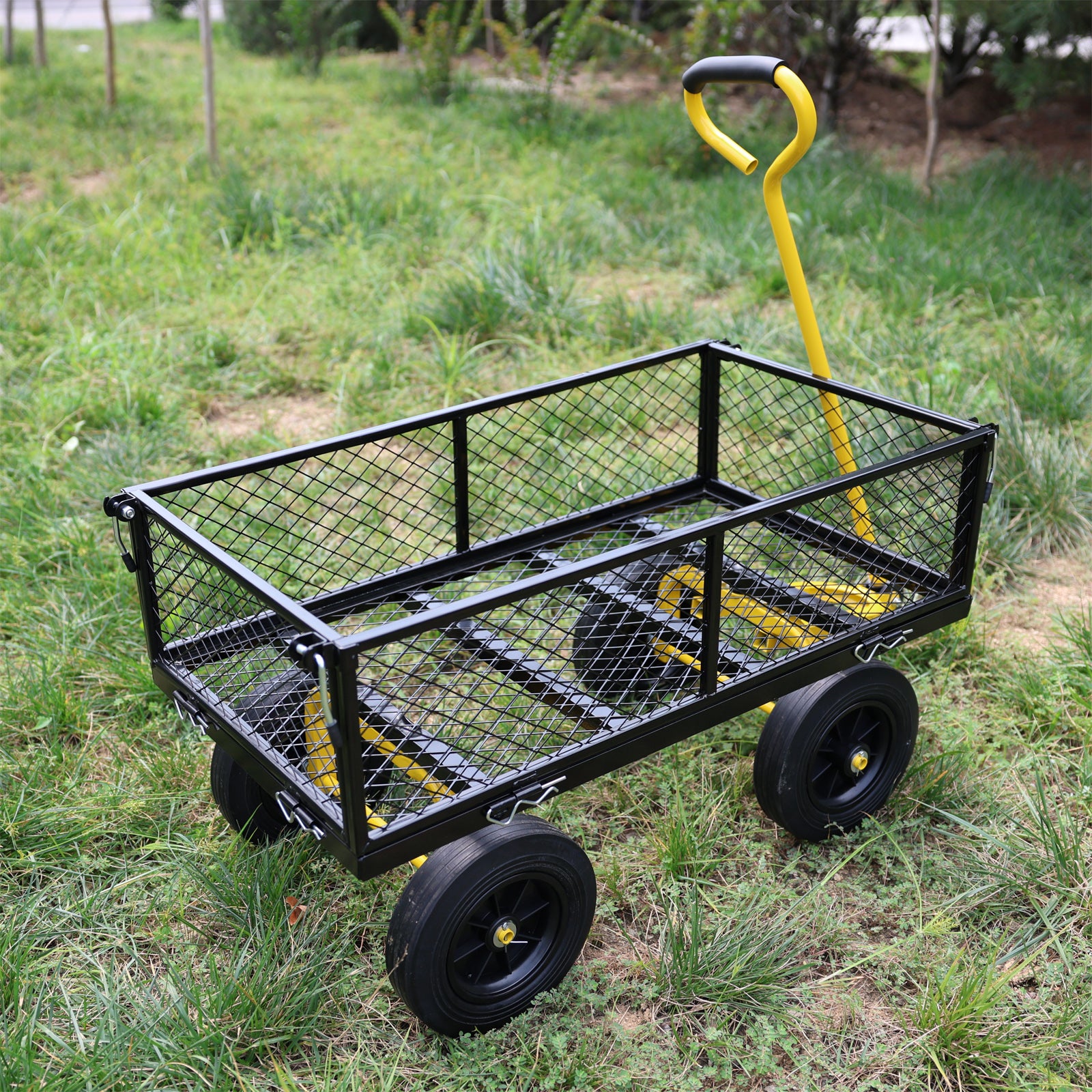 Black metal utility garden cart with yellow handle and black wheels on grass