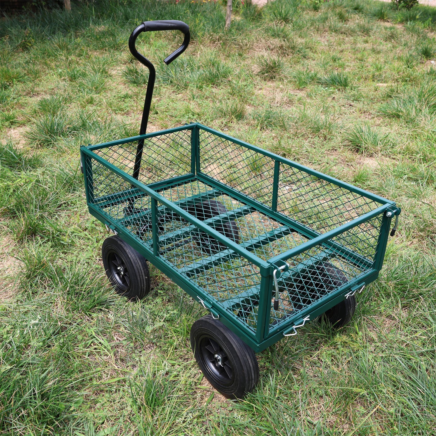 Green metal garden cart with mesh sides and black wheels on grass