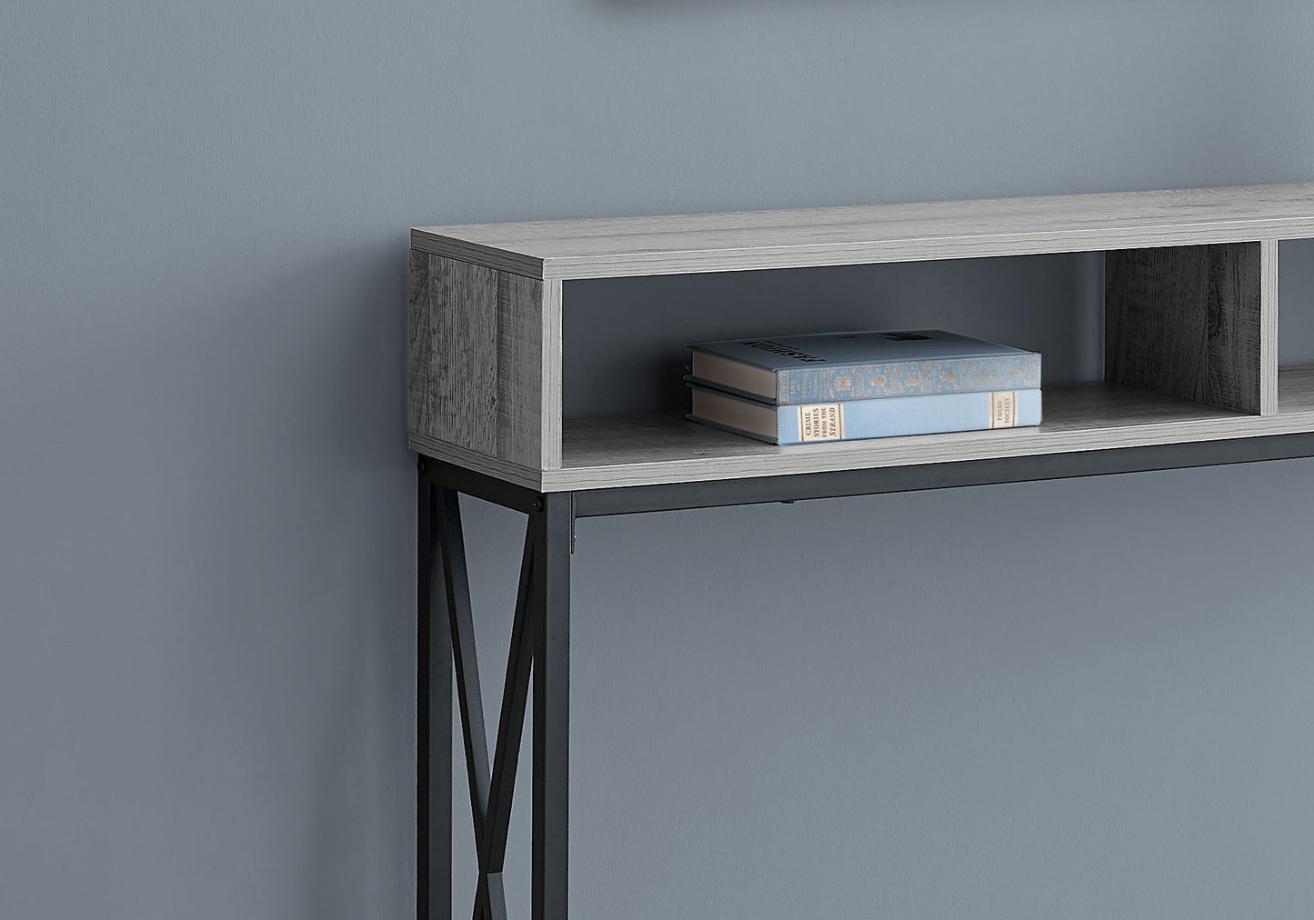 Grey wood console table with black metal legs and two open shelves holding books