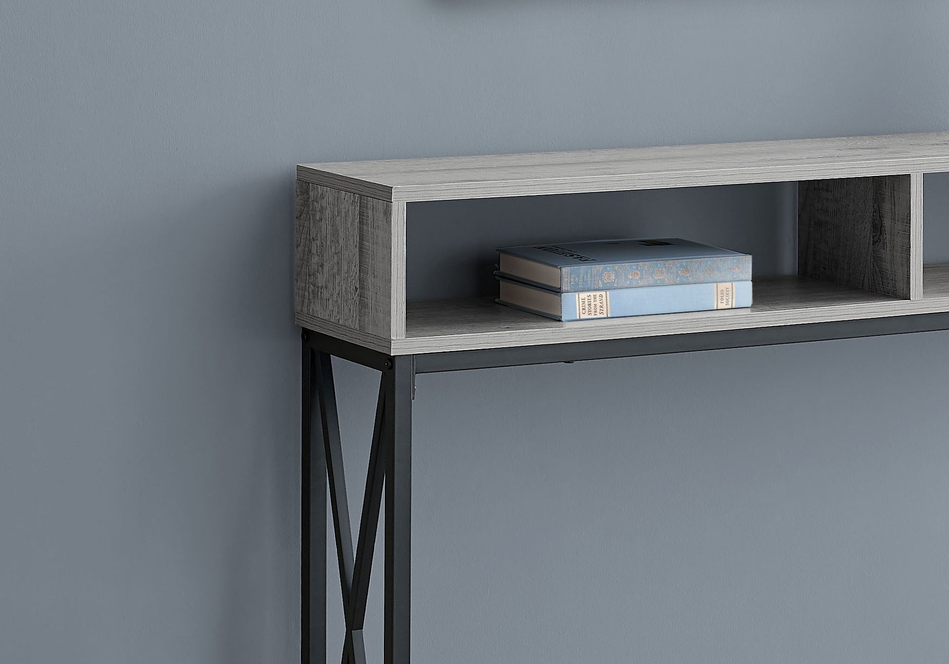 Grey wood console table with black metal legs and two open shelves holding books