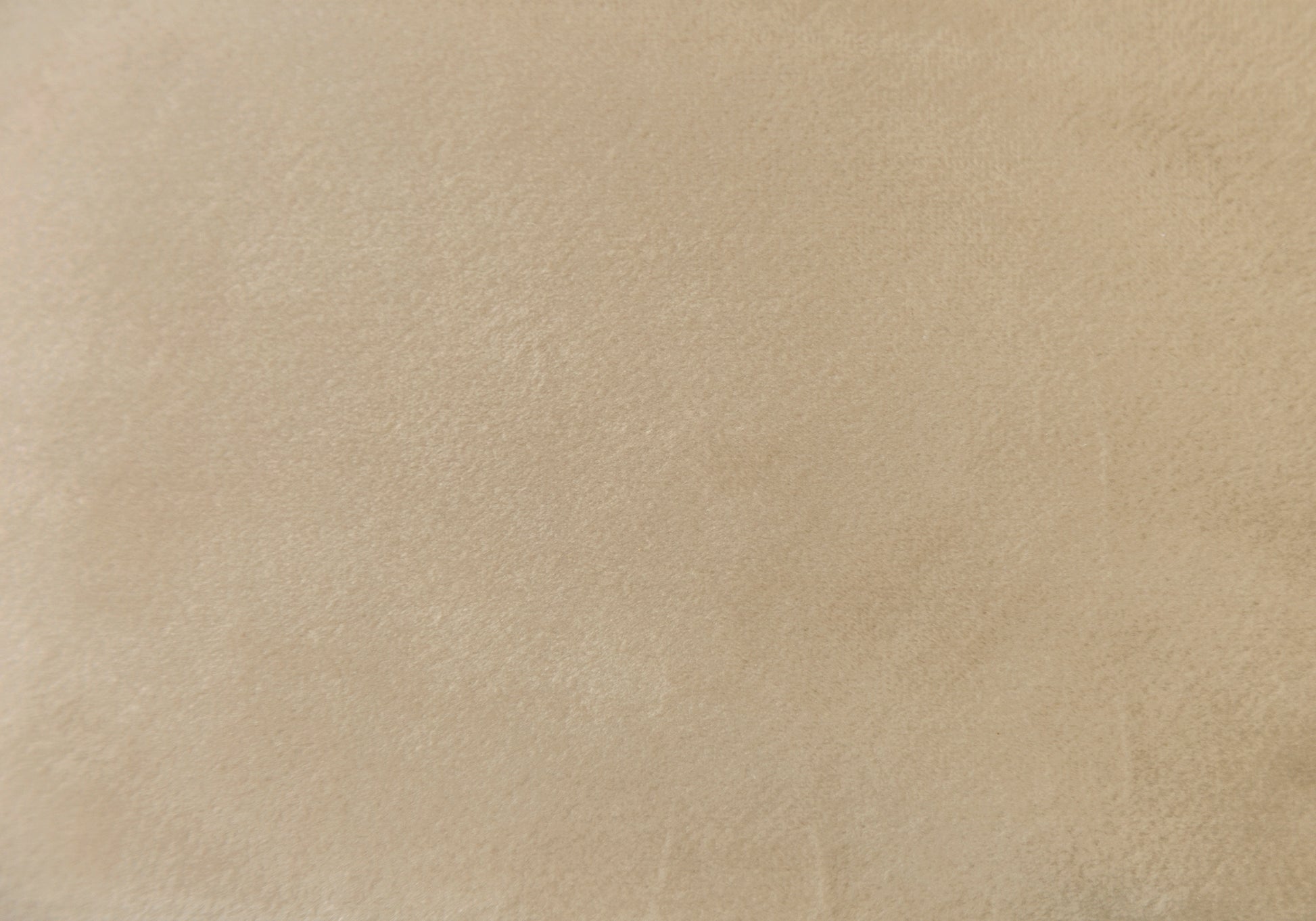 Closeup of soft beige suede fabric texture ideal for upholstery or fashion applications