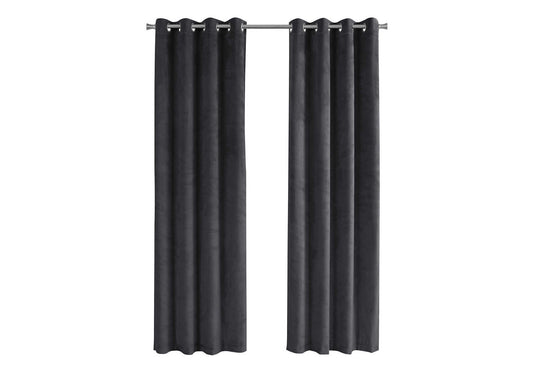 Two dark grey velvet grommet curtains hanging on a silver curtain rod