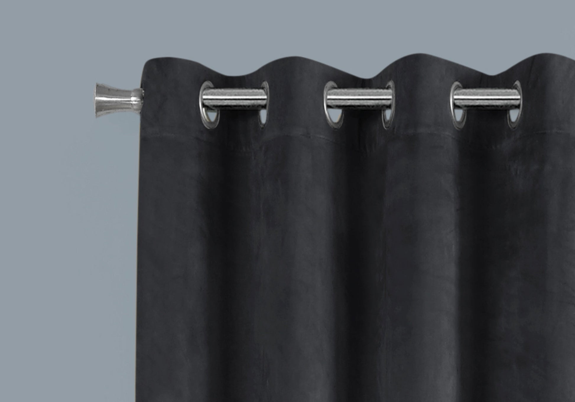 Closeup of a charcoal grey velvet grommet curtain with a silver curtain rod accent