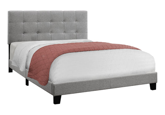 Tufted grey fabric bed frame with a coral quilt and white linens