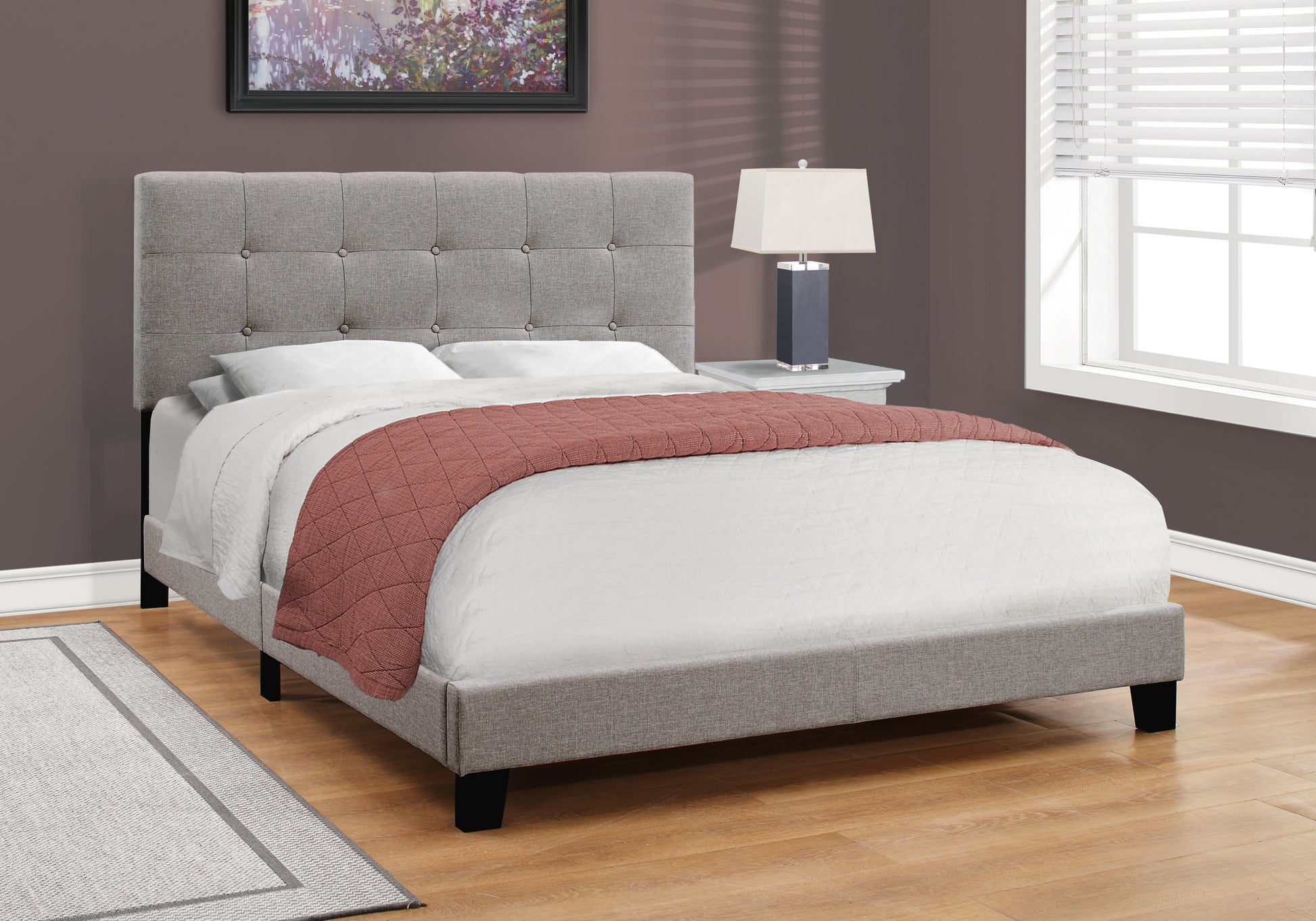Gray upholstered queen bed frame with tufted headboard and coral throw blanket