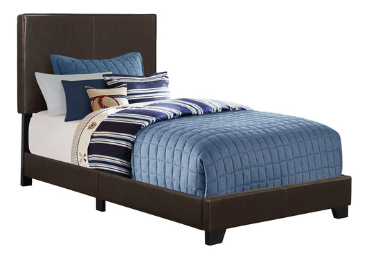 Brown faux leather twin bed frame with blue quilted comforter and striped pillows