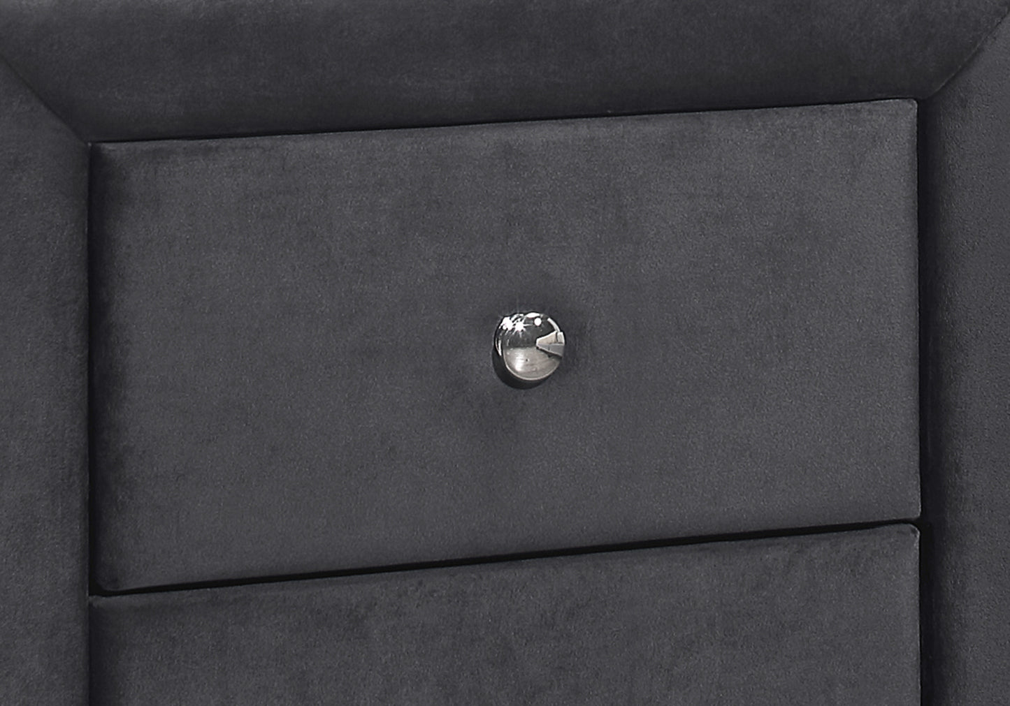 Closeup of a dark grey velvet upholstered drawer front with a silver crystal knob