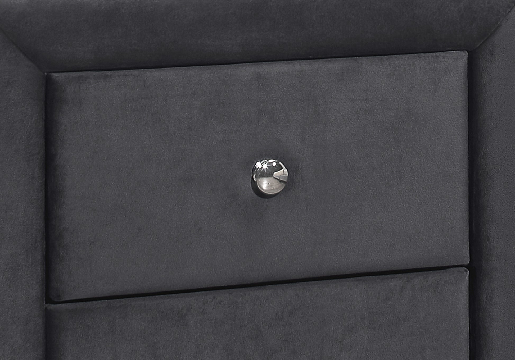 Closeup of a dark grey velvet upholstered drawer front with a silver crystal knob