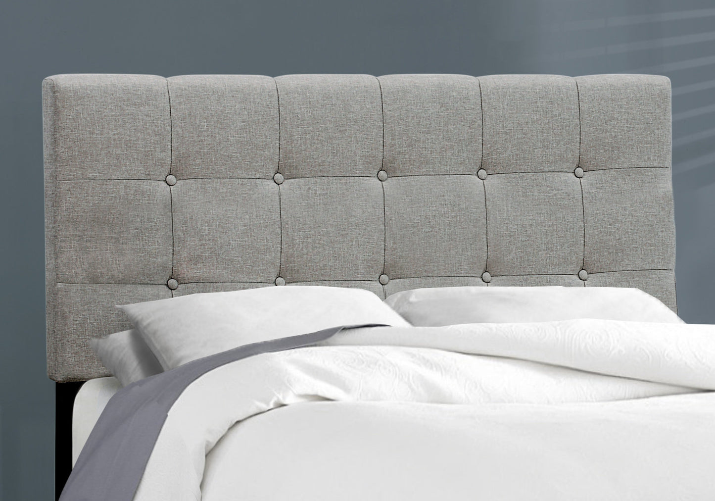 Tufted grey fabric headboard with button tufting adds elegance to bedroom decor