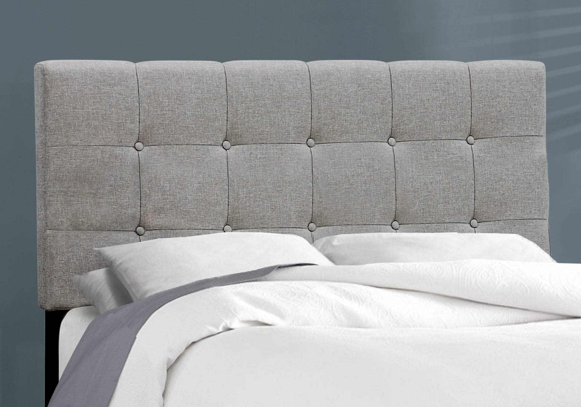 Tufted grey fabric headboard with button tufting adds elegance to bedroom decor