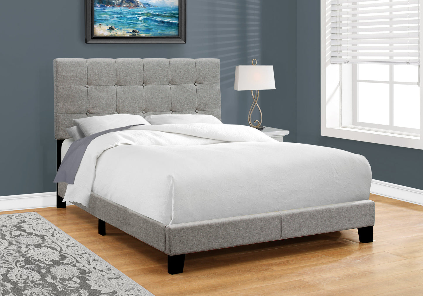 Grey upholstered twin bed with tufted headboard and white linens