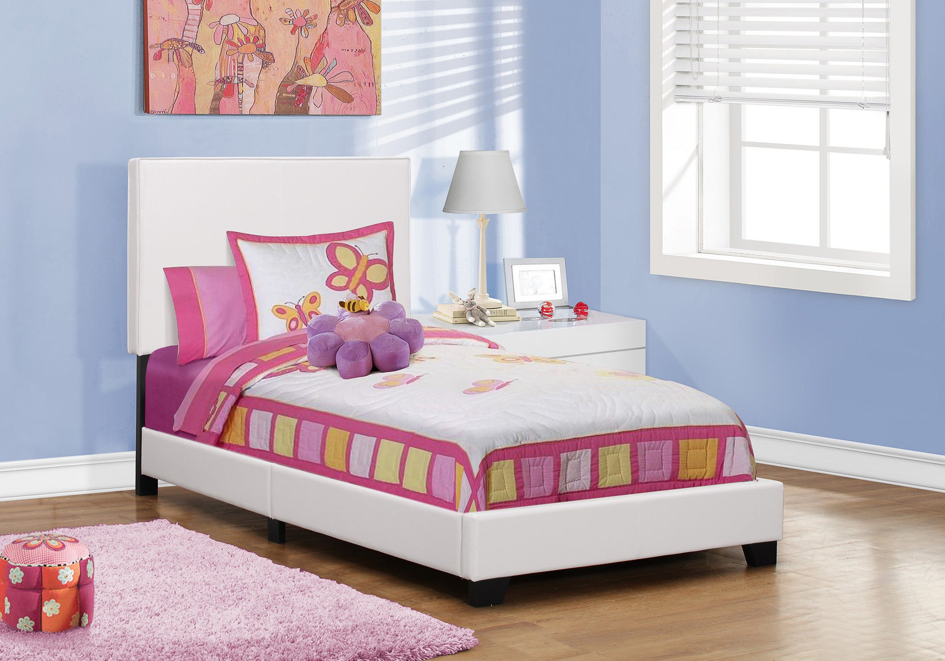 White upholstered twin bed with colorful butterfly bedding and pink accents