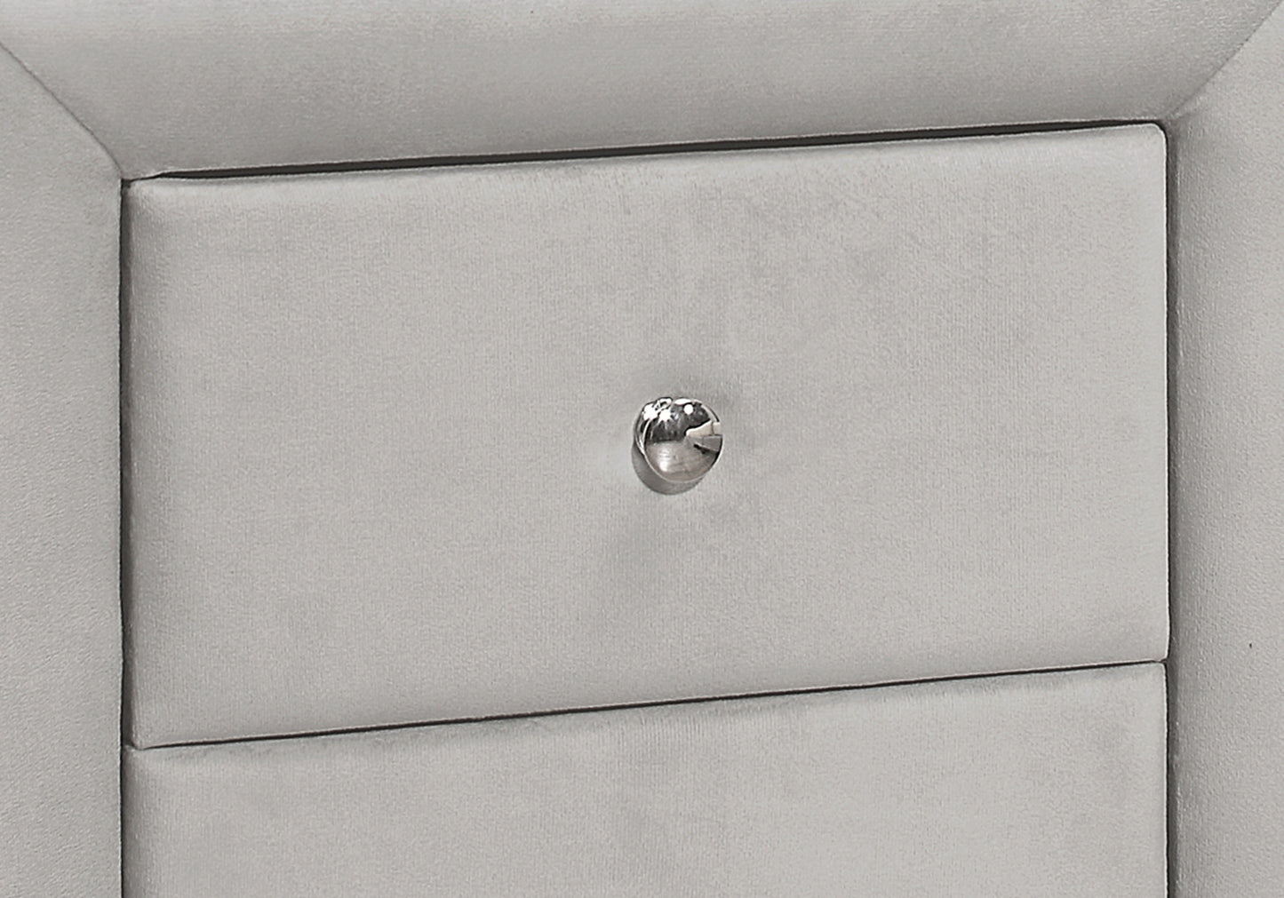 Closeup of a light grey velvet upholstered drawer front with a crystal knob