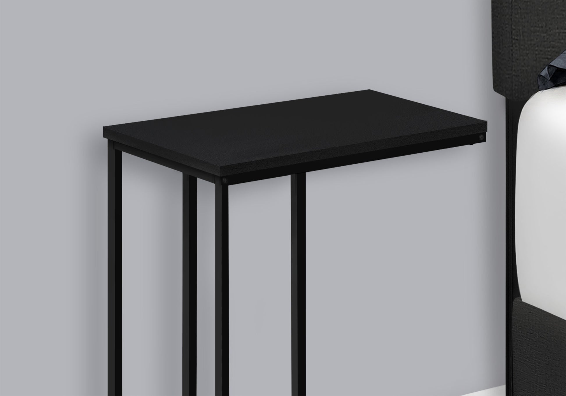 Black Cshaped end table with metal legs perfect for use next to a bed
