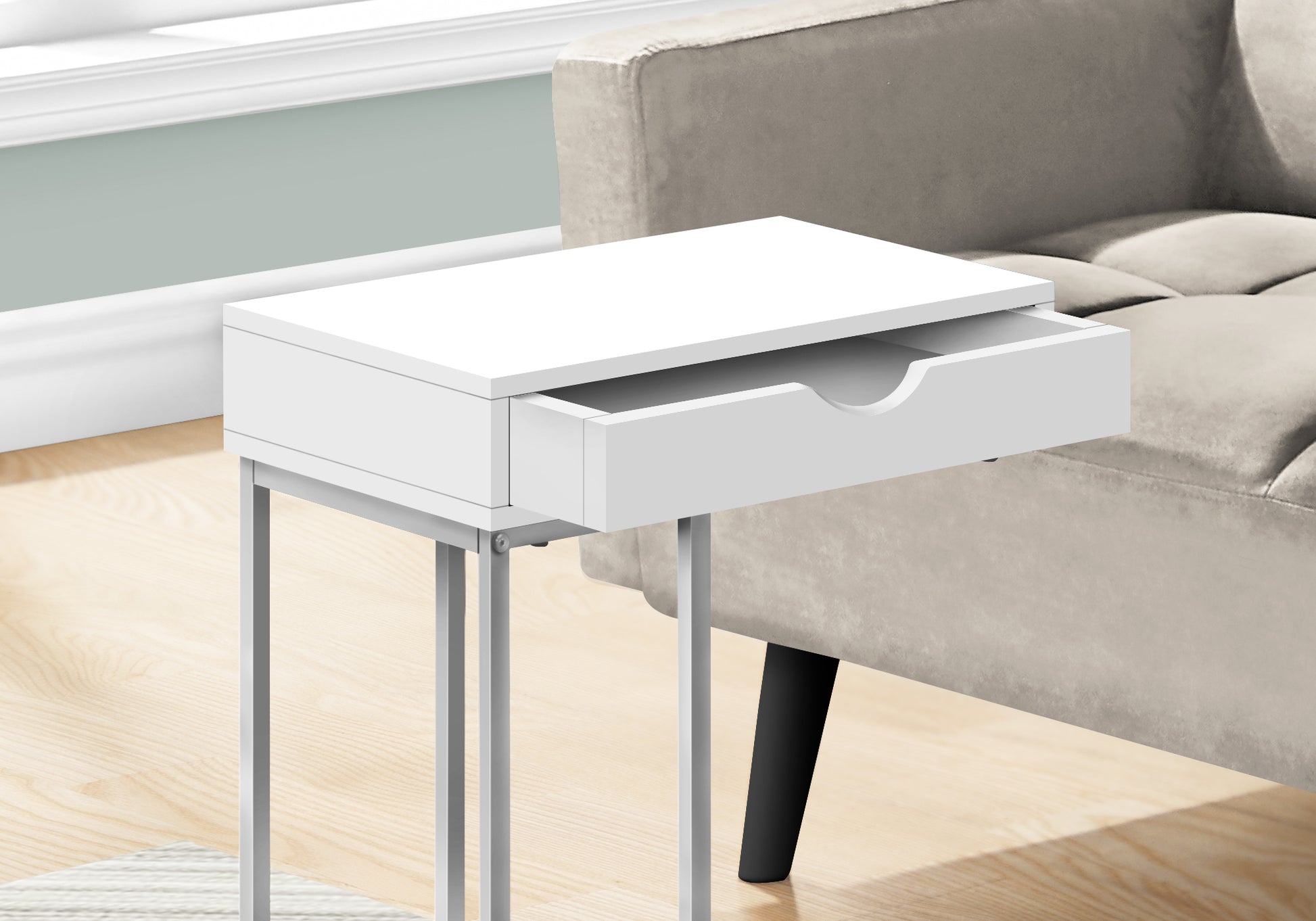 Slim white end table with open drawer and silver metal legs next to sofa