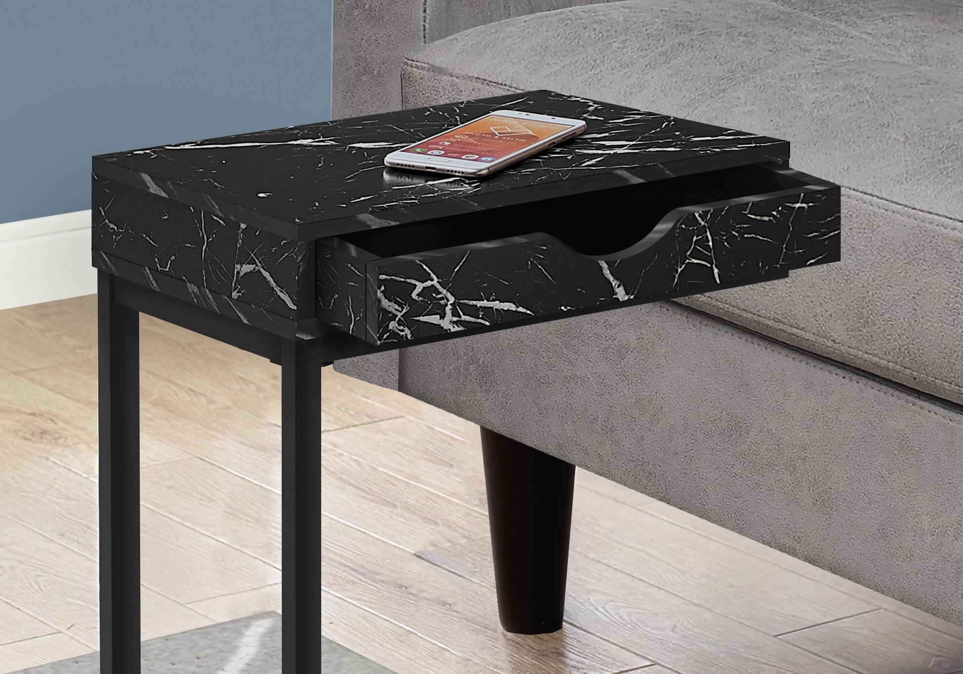 Black marble accent table with open drawer and phone