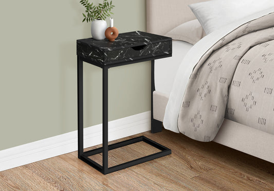 Black marble end table with drawer and metal frame beside bed