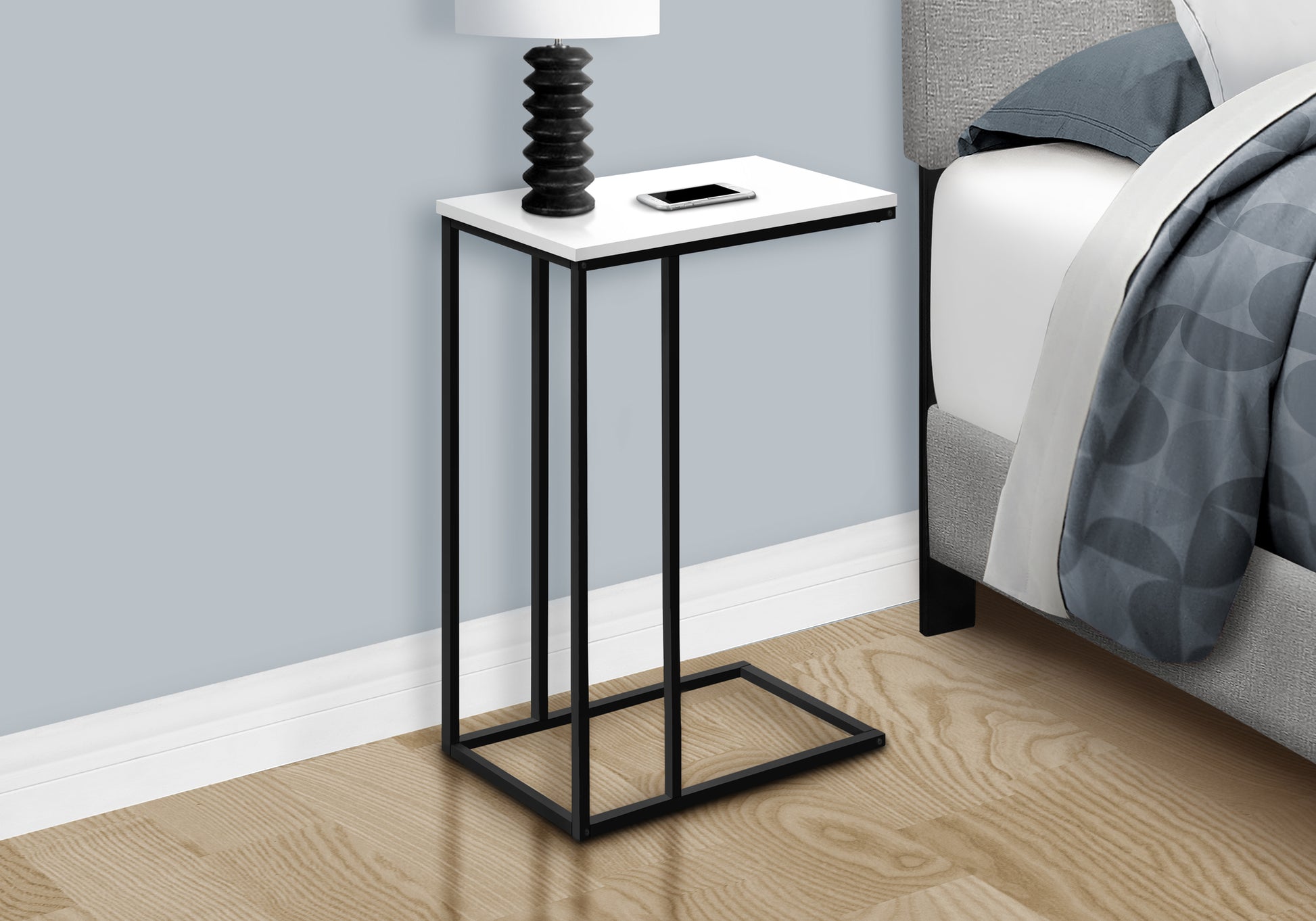 White and black metal Ctable with a smartphone and lamp perfect for bedside organization