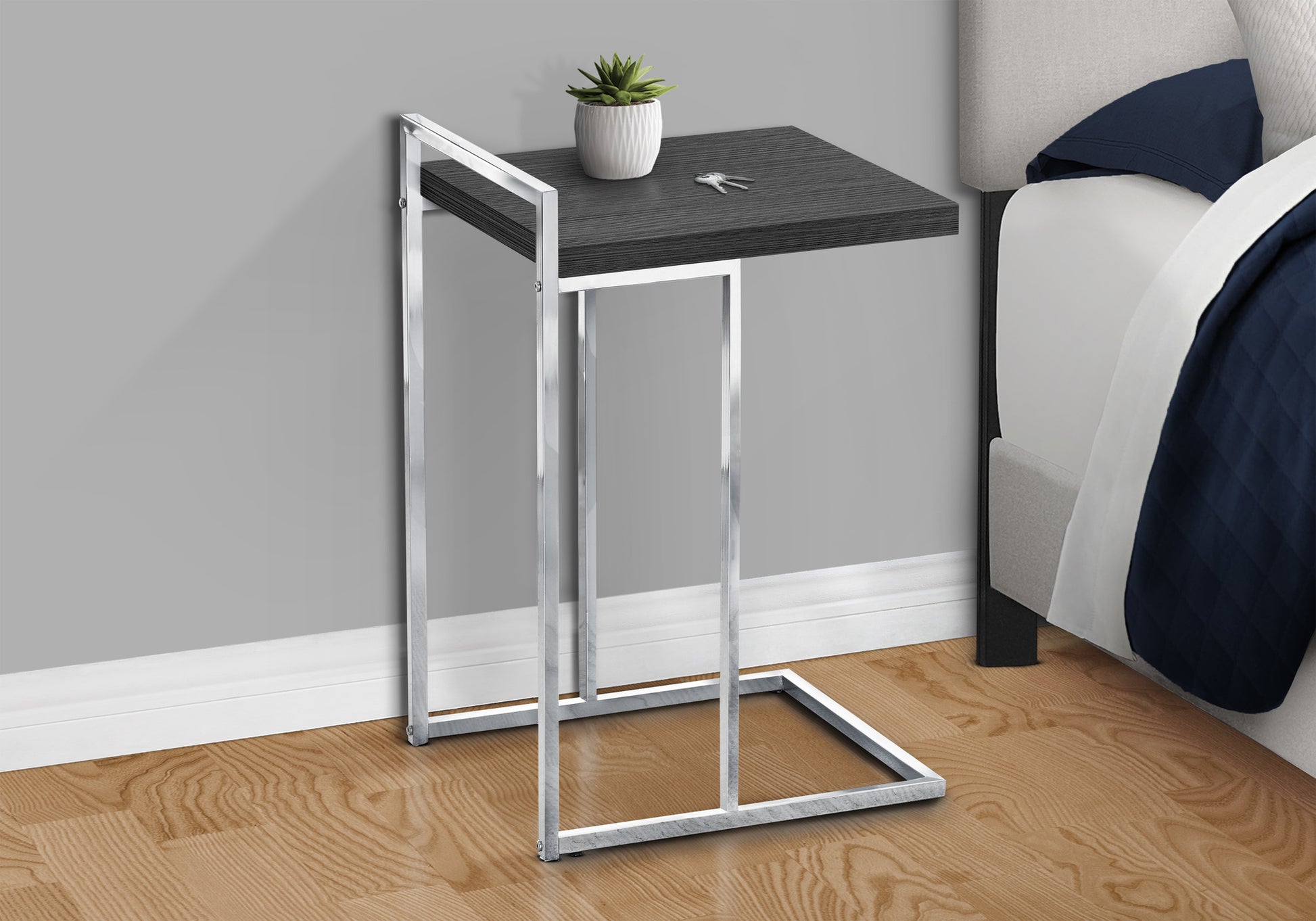 Modern charcoal grey side table with chrome frame beside bed