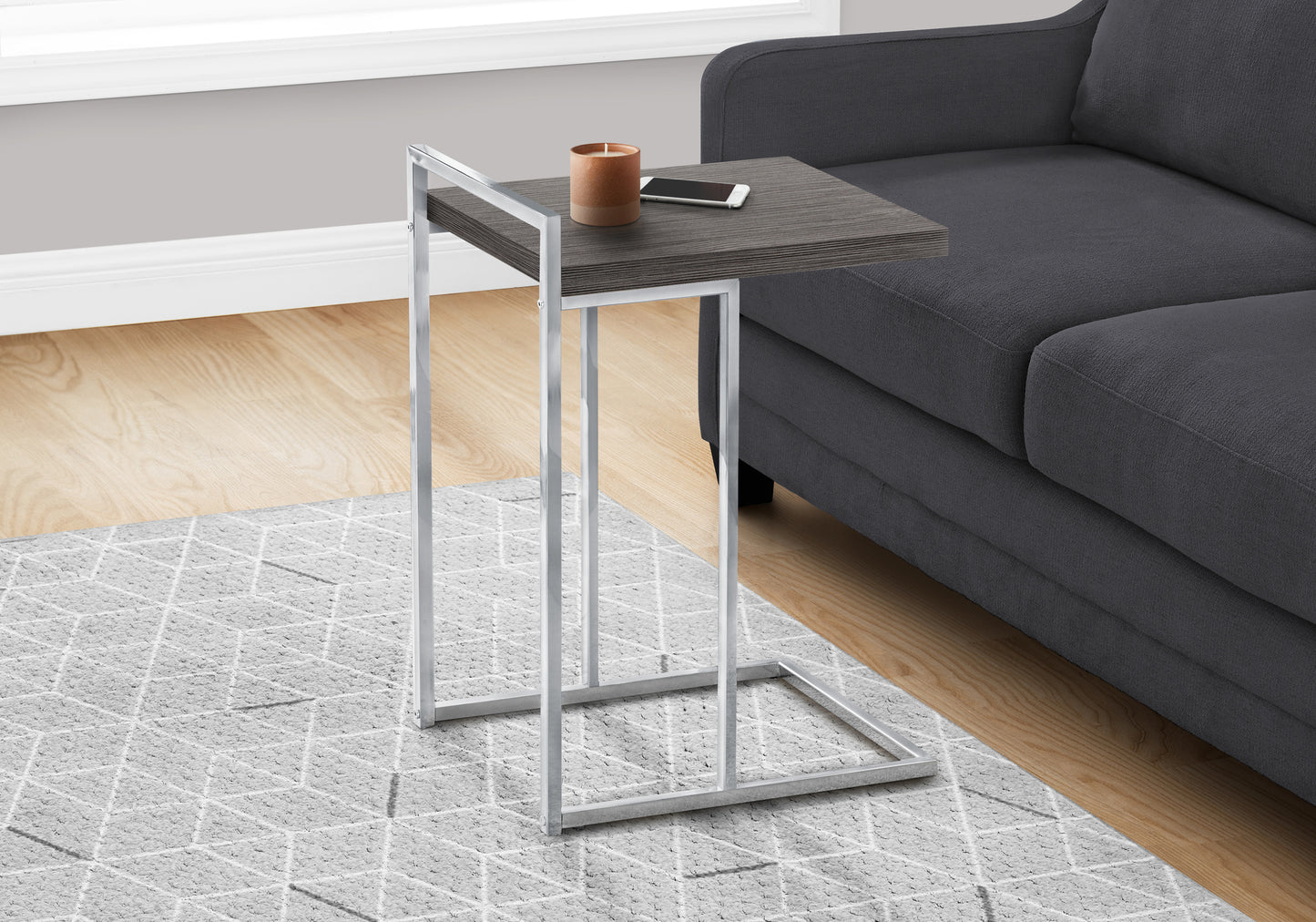 Gray woodgrain ctable with a chrome base holding a candle and smartphone