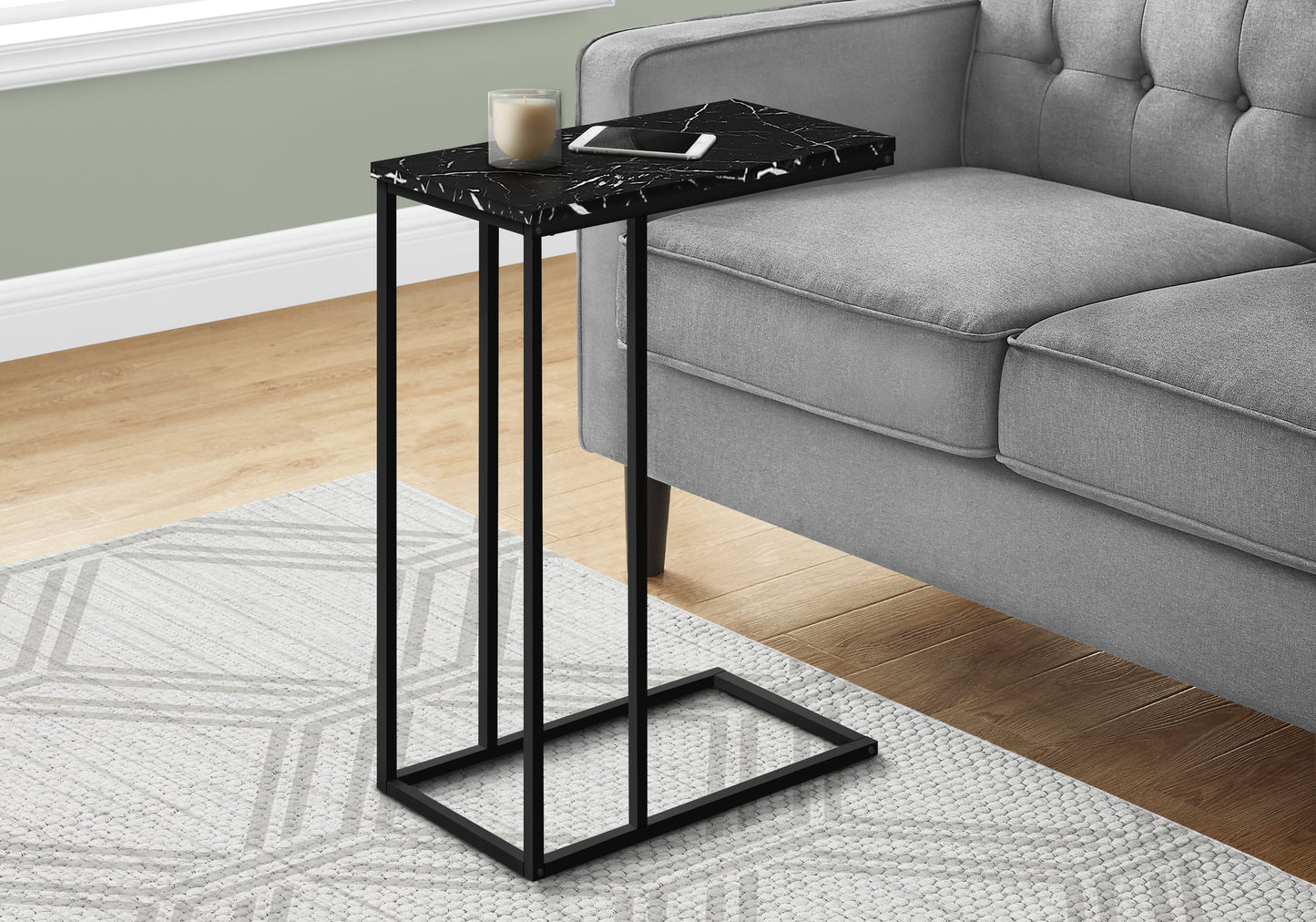 Black marble effect ctable with phone and candle on top beside grey sofa